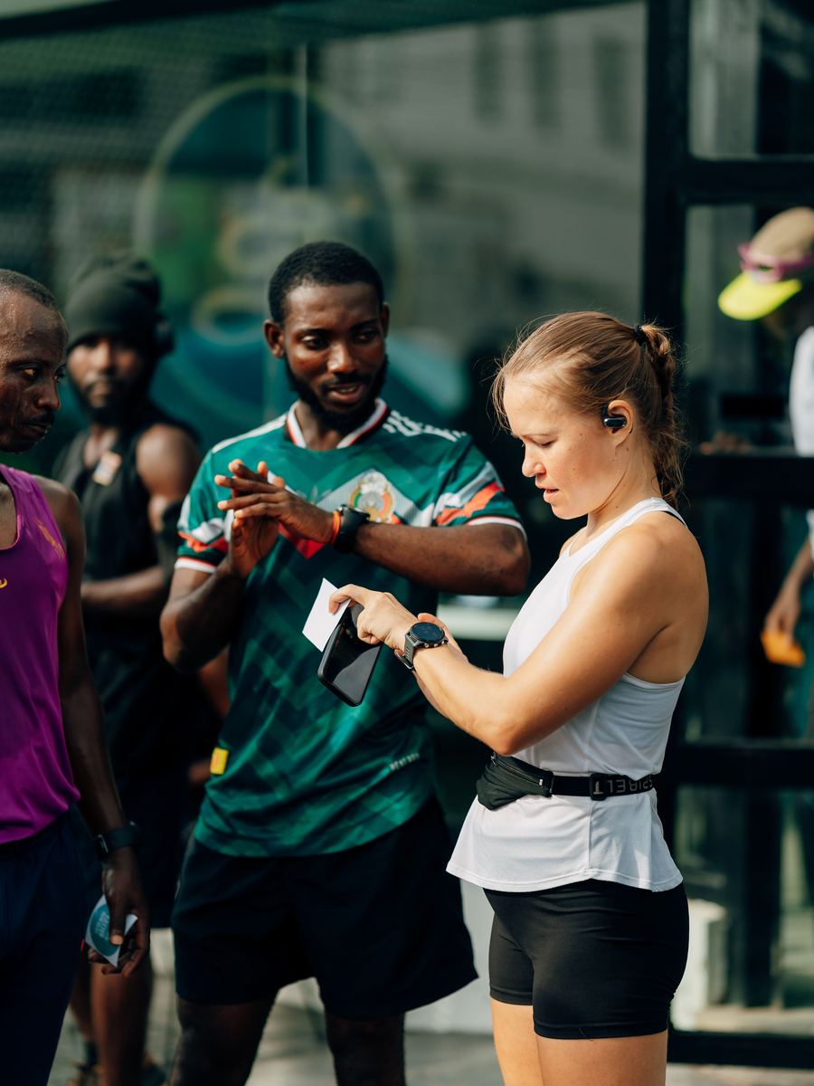 A runner setting her watch at the start, others waiting around her